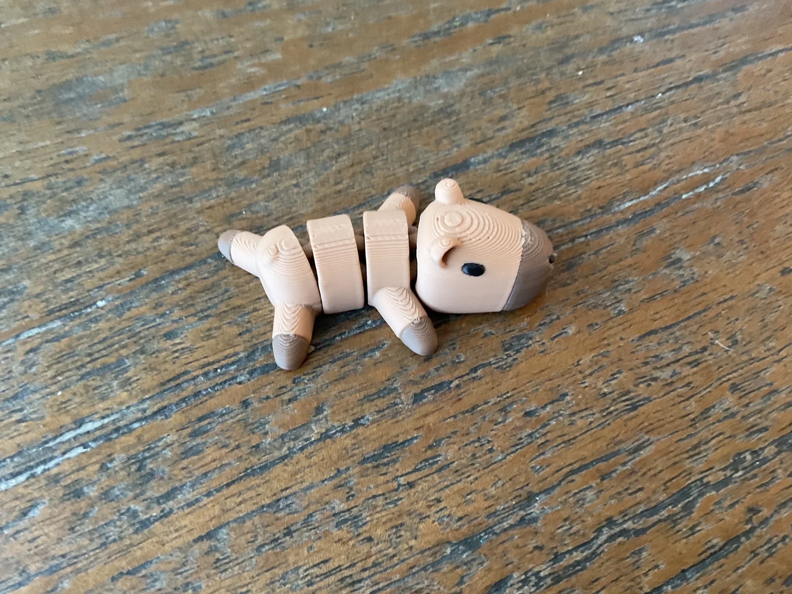 Tan articulated Baby Capybara standing on a wooden table