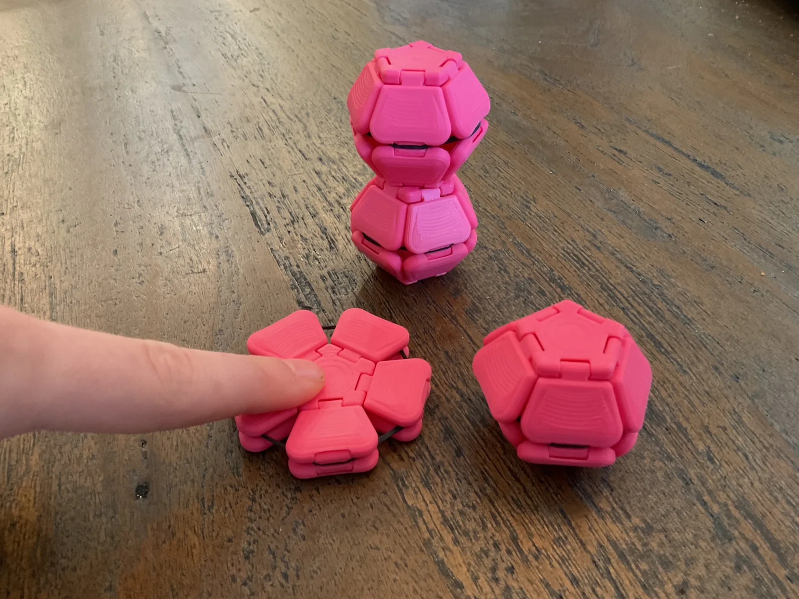 Pink Pentaclicks in several shapes with one being pressed